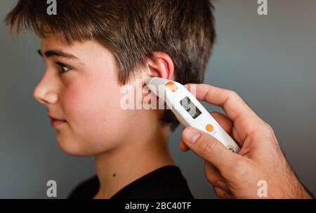 Zwischen Jungen bekommen Temperatur mit einem Ohrthermometer genommen. Stockfoto