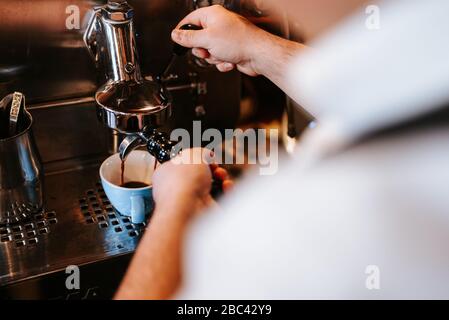 Ein Mann in einem Café bereitet Espresso-Kaffee zu. Kaffeemaschine und Tasse Stockfoto