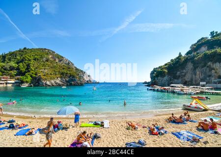 Touristen entspannen im klaren Wasser am sandigen Strand Palaiokastritsa und an der Bucht auf der ägetischen Insel Korfu, Griechenland. Stockfoto