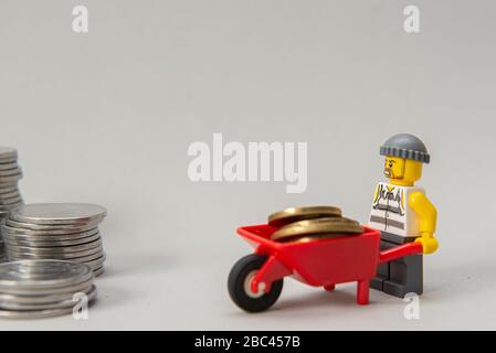 Florianopolis, Brasilien, 28. März 2020: Miniaturen von Bankräubern, die Geld stehlen. Diebe, die Münzen auf weißem Hintergrund tragen. Selektiver Fokus. LEGO m Stockfoto
