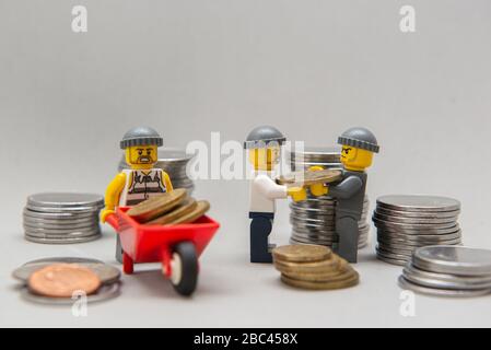 Florianopolis, Brasilien, 28. März 2020: Miniaturen von Bankräubern, die Geld stehlen. Diebe, die Münzen auf weißem Hintergrund tragen. Selektiver Fokus. LEGO m Stockfoto