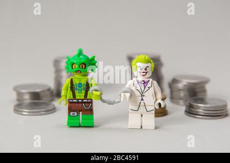 Florianopolis, Brasilien, 28. März 2020: Joker und Monsterminifigure handgeschlüpft miteinander mit Münzen im Hintergrund. LEGO Minifiguren sind manufa Stockfoto