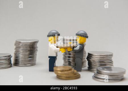 Florianopolis, Brasilien, 28. März 2020: Miniaturen von Bankräubern, die Geld stehlen. Diebe, die Münzen auf weißem Hintergrund tragen. Selektiver Fokus. LEGO m Stockfoto
