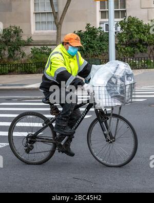 New York, USA. April 2020. Ein Liefermann trägt eine Gesichtsmaske, als er mit seinem Fahrrad in New York City fährt. Heute sagte die Regierung, dass Newyorkers ihre Gesichter bedecken sollten, wenn sie nach draußen gehen, um eine Ausbreitung des Coronavirus zu verhindern. Kredit: Enrique Shore/Alamy Live News Stockfoto