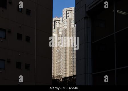 Die Zwillingstürme des Tokyo Metropolitan Government Building zwischen hohen, dunklen Gebäuden Shinjuku, Tokio, Japan Stockfoto