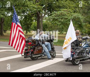 2 Veteranen lehnen sich an ihre Motorräder. Man hat eine große anericanische Flagge und eine hat eine große Goldstern-Mutter-Flagge. September 2015, NJ USA Stockfoto