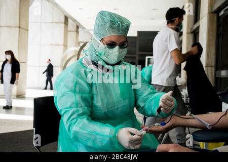 Eine in einen Schutzanzug gekleidete Krankenschwester nimmt während des Spendervorgangs Blutproben von einem Spender ab.aufgrund einer Kovid-19-Pandemie werden intensive Blutspenden von öffentlichen Gesundheitsdiensten und Spenderzentren organisiert, um möglichen Blutvorräten begegnen zu können. Stockfoto