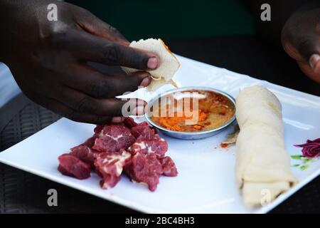 Ein äthiopischer Mann, der Injera Be Reifen siga isst (Injera mit rohem Fleisch) Stockfoto