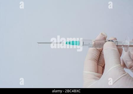 Spritze mit weißen Latexhandschuhen in Händen gehalten Stockfoto