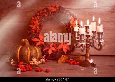 Herbstkranz und Stillleben mit altem Kerzenstift aus Kerzenleuchtern, Kerzen, Flamme. Holzpilze, Beeren auf Holz. Design für saisonale Herbst-Geburtstage Stockfoto