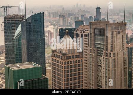 Shanghai, Pudong, Lujiazui, China - 4. Mai 2010: HSBC-Gebäude, teilweise versteckt unter anderen braunen Stein- und grünen Glaskratzern mit Smog über anderen Stockfoto