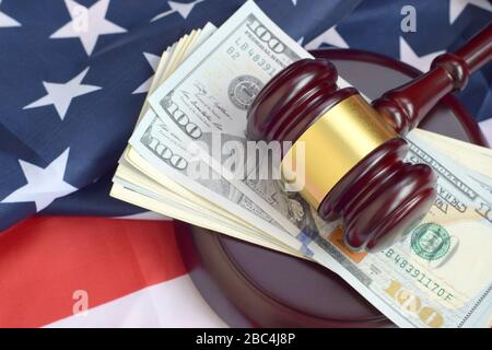 Richter Gavel und Geld auf der Flagge der Vereinigten Staaten von Amerika. Viele Hundert Dollar-Scheine unter Richter-Bosheit auf US-Flagge. Urteilsvermögen und Bestechungskonzept Stockfoto