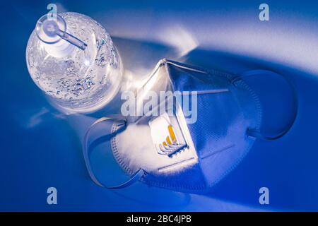 Antiseptisches Handgel und N95-Maske auf weißem Tisch mit dramatischem Lichteffekt, Gesundheitskonzept Stockfoto