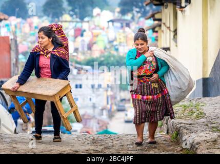 Zwei Frauen gehen auf den Markt, um ihr Geschäft in Chichicastenango, Guatemala, einzurichten. Stockfoto
