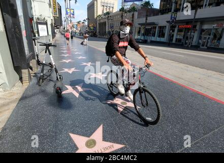 Los Angeles, Kalifornien, USA. April 2020. Ein Mann, der eine Gesichtsmaske trägt, reitet auf dem Hollywood Walk of Fame. Der Bürgermeister von Los Angeles rät der Öffentlichkeit, beim Aussteigen jede Art von Gesichtsschutz zu tragen - auch einen Schal oder ein anderes Kleidungsstück - um die Ausbreitung des Coronavirus zu verringern. Kredit: Ringo Chiu/ZUMA Wire/Alamy Live News Stockfoto