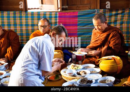 YASOTHON, THAILAND - 12. JANUAR: Thailändische Leute geben in Retro Speisen der Tradition des Almsgiving mit klebrigem Reis und Essen in die buddhistische Almosenschale Stockfoto