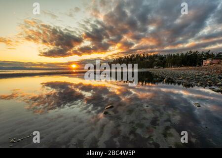 Erstaunliche Wolken-Reflexion bei Sonnenaufgang entlang des Ozeans in der Kye Bay auf Vancouver Island, British Columbia, Kanada. Stockfoto