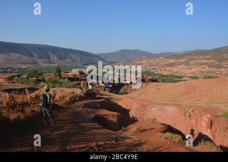 Ein Reiseleiter führt Sie durch ein Dorf im Amazigh-Berber-Gebirge in der Nähe von Asni im marokkanischen Atlasgebirge. Stockfoto