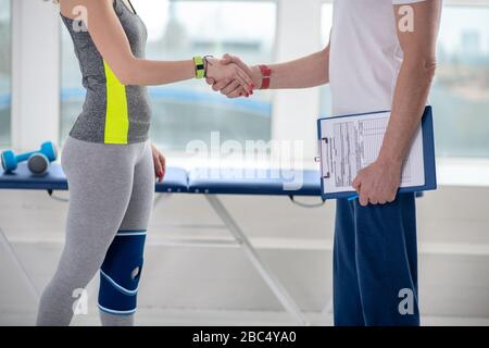 Männliche Physiotherapeutin und weibliche Patientin schütteln die Hände Stockfoto