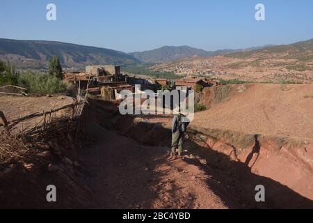 Ein Reiseleiter führt Sie durch ein Dorf im Amazigh-Berber-Gebirge in der Nähe von Asni im marokkanischen Atlasgebirge. Stockfoto