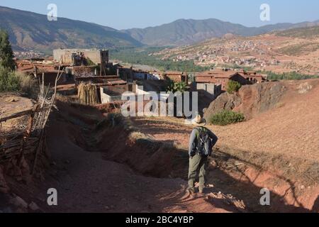 Ein Reiseleiter führt Sie durch ein Dorf im Amazigh-Berber-Gebirge in der Nähe von Asni im marokkanischen Atlasgebirge. Stockfoto