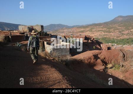 Ein Reiseleiter führt Sie durch ein Dorf im Amazigh-Berber-Gebirge in der Nähe von Asni im marokkanischen Atlasgebirge. Stockfoto