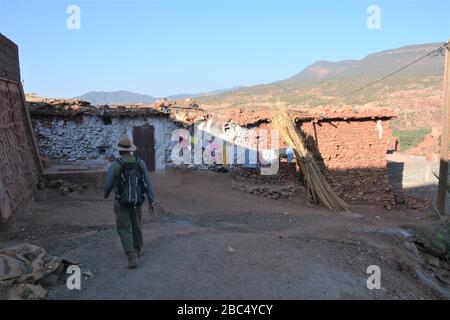 Ein Reiseleiter führt Sie durch ein Dorf im Amazigh-Berber-Gebirge in der Nähe von Asni im marokkanischen Atlasgebirge. Stockfoto