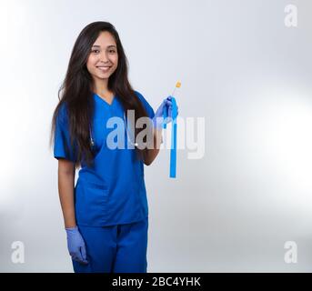 Eine junge Krankenschwester in blauen Schrubben steht bereit, eine Blutprobe zu machen. Stockfoto