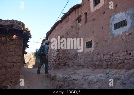 Ein Reiseleiter führt Sie durch ein Dorf im Amazigh-Berber-Gebirge in der Nähe von Asni im marokkanischen Atlasgebirge. Stockfoto