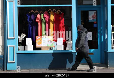 Ein Mann läuft am Regenbogenfenster des Strathcarron Hospice Charity Shop in der Hauptstraße in Callander, Perthshire, vorbei, während Großbritannien weiterhin in Sperrungen bleibt, um die Ausbreitung des Coronavirus einzudämmen. Stockfoto