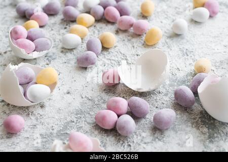 Osterzusammensetzung mit Mini-Schokoladeneiern in Pastellfarben auf grauem Betonhintergrund. Frohe Ostern. Stockfoto
