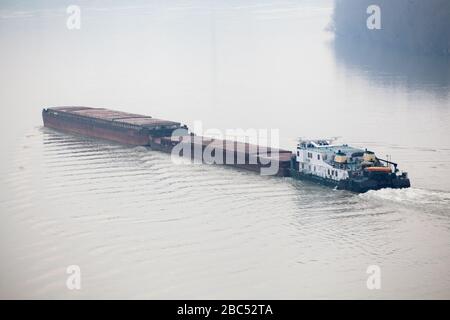 Draufsicht über Tugboat, der einen schweren Kahn auf den Fluss treibt Stockfoto