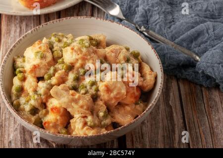 Geschmortes Hühnerfilet mit grünen Erbsen auf einem Holztisch Stockfoto