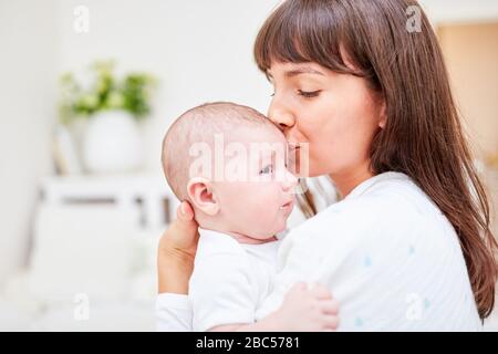 Liebevolle Mutter gibt ihrem Baby einen Kuss auf die Stirn Stockfoto