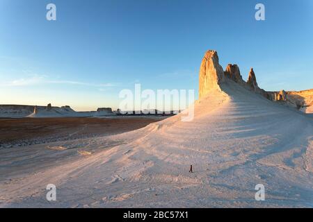 Frau in roter Jacke zu Fuß an Felsformationen, Kalksteinberge, Ustyurt, Boszhira, Kaspische Depression Wüste, Aktau, Mangystau, Kasachstan Stockfoto