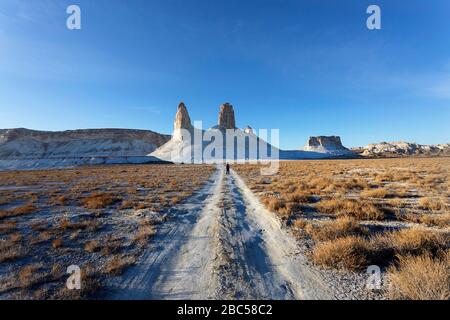 Silhouette auf Schotterstraße zu Kalksteinbergen in der Ustyurt Plateau bei Boszhira in Kaspischen Depression Wüste, Aktau, Mangystau Region, Kasachstan Stockfoto