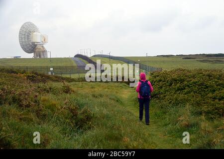 Einreisende Frau auf dem Weg zum GCHQ Bude Radar Hörstation auf dem South West Coastal Path, North Cornwall, England, Großbritannien. Stockfoto