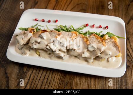 Huhn auf geriebenem Gnocchi in Sahnesauce aus Pilzen und Räucherkäse auf dem Tisch Stockfoto