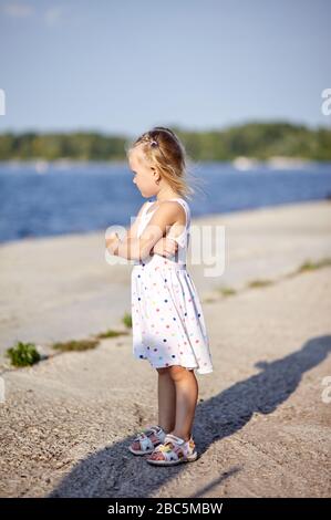 Trauriges Kind, einsames kleines Mädchen, das auf Wasser beobachtet Stockfoto