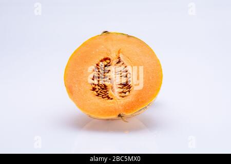 Melone in zwei Hälften geschnitten mit sichtbaren Samen im Inneren isoliert vor einem weißen Hintergrund Stockfoto