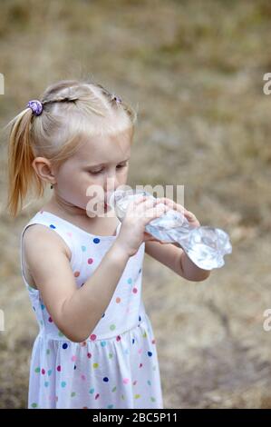 Kleines Mädchen trinkt Wasser aus einer Flasche im Park Stockfoto