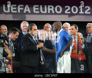 Italiens Mario Balotelli schüttelt die Hand von UEFA-präsident Michel Platini, als er nach dem Spiel die Medaille seiner Nächstplatzierten sammelt Stockfoto