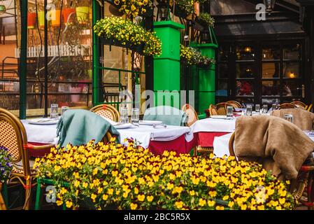 Wunderschönes Café/Restaurant im Retro-Stil - Außenstühle und Tische im Freien und frische Blumen Stockfoto