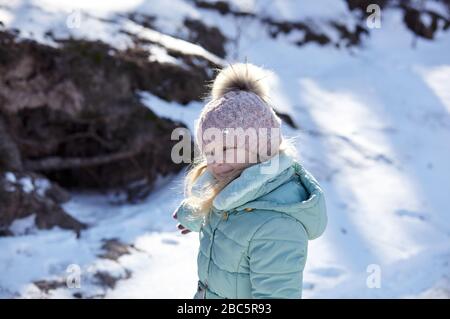 Kleines Mädchen in farbenfroher Kleidung, das draußen spielt. Aktive Freizeit mit Kind im Winter an kalten Tagen Stockfoto