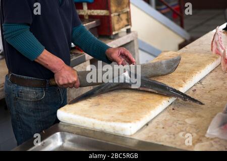 FUNCHAL, PORTUGAL - 15. FEBRUAR 2020: Unidentifizierter Mann schneidet Haifischschwanz bei Mercado dos Lavradores (Bauernmarkt) in Funchal auf der Insel Madeira, Po Stockfoto