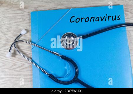 Coronavirus auf einer blauen Datei und einem schwarzen Stethoskop Stockfoto