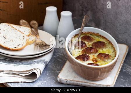 Gebackene Fleischbällchen in cremiger Soße und Brotscheiben mit Flachs auf Betongrund. Stockfoto