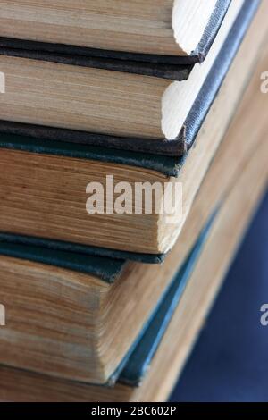 Alte Bücher mit ausgefransten Einbänden auf einem dunklen Tisch. Stockfoto