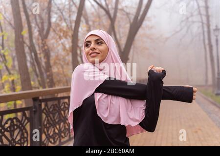 Positive Dame im Hijab, die Arm zieht und ein lächelndes Stockfoto Stockfoto