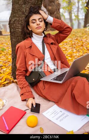Entspannte verträumte Frau beim Picknick im Parkstockfoto Stockfoto